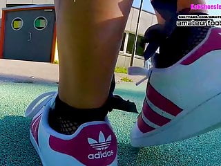 Girl in red Adidas Superstars does shoeplay, dipping fishnet socks 