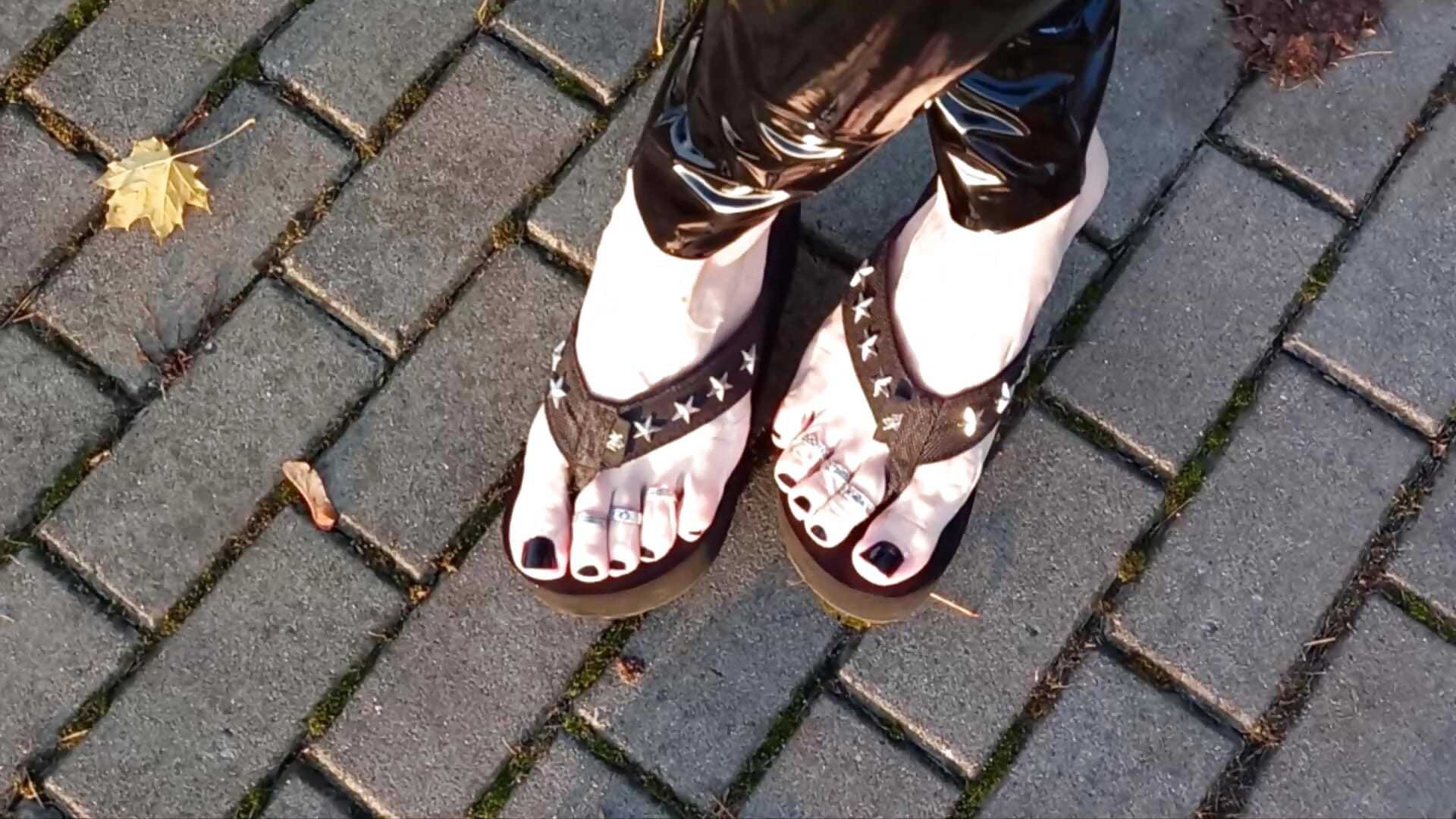 crossdresser walks in public in latex leggings and flip-flops on a platform, showing off his sexy feet