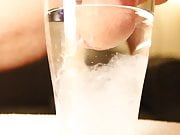 Close-up cumshot of circumcised cock in glass of water